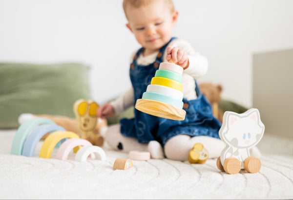 Kind 1 jaar, baby 1 jaar speelt met houten speelgoed, stapeltoren en trekfiguur.