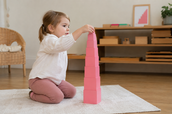 Kind speelt met Montessori speelgoed, de pink tower in een woonkamer