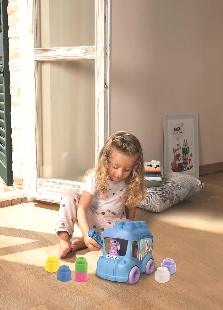 Klein meisje speelt met Clementoni Clemmy Stitch Activiteiten bus, kleurrijke blokkenset voor peuters binnen.