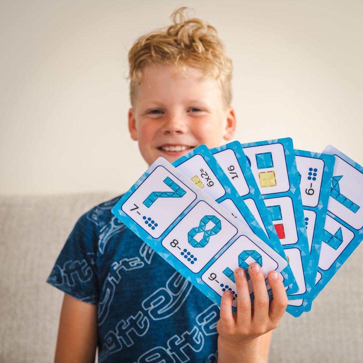 Blije jongen toont Coblo opdrachtkaarten met cijfers ontwikkeld met leerkrachten voor school en kinderopvang