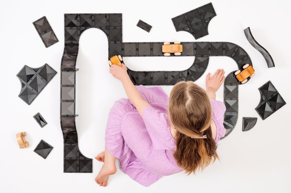 Meisje speelt met Connetix Creative Roads Pack 48pc magnetisch speelgoed en houten autootjes