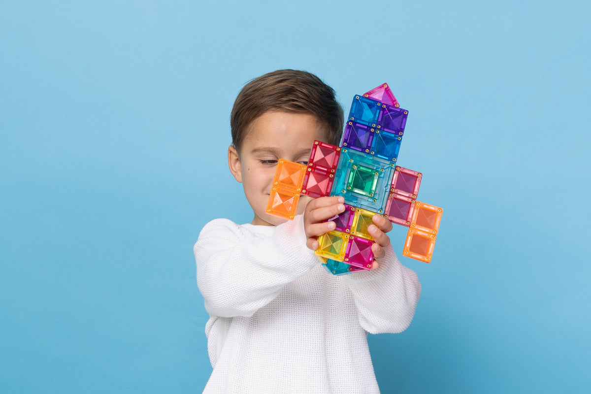 Jongen speelt met Connetix Bright Portal Pack 48pc en bouwt een raket van magnetische tegels