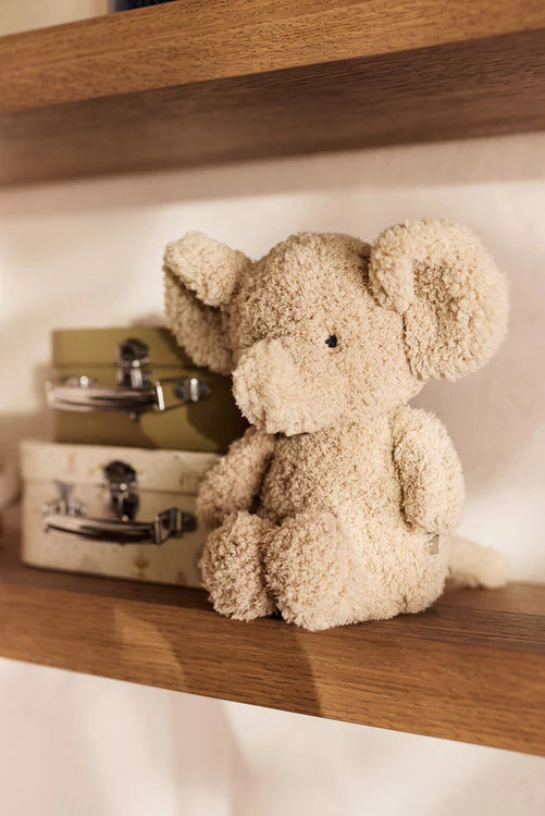 Zittende Jollein knuffel olifant op houten plankje naast koffertjes, decoratief en geschikt als baby cadeau of kraamcadeau.