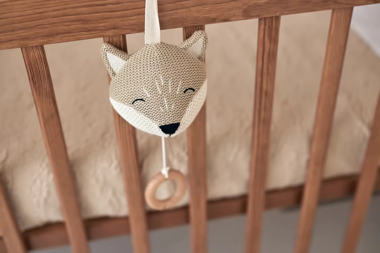 Beige Jollein Muziekdoosje Fox bevestigd aan houten babybed, een zachte muziekhanger perfect als baby cadeau.