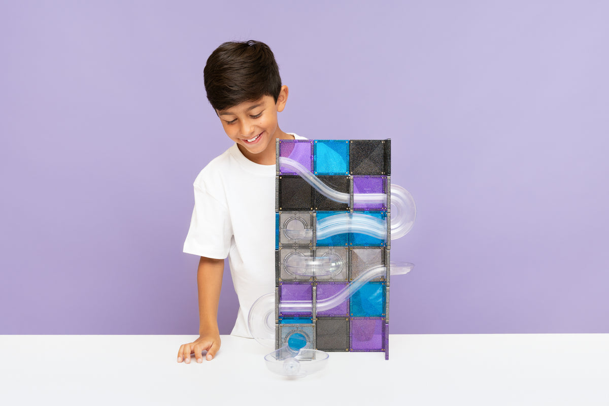 Kind bewondert zelfgebouwde Connetix magnetische knikkerbaan met galaxy kleuren en transparante elementen