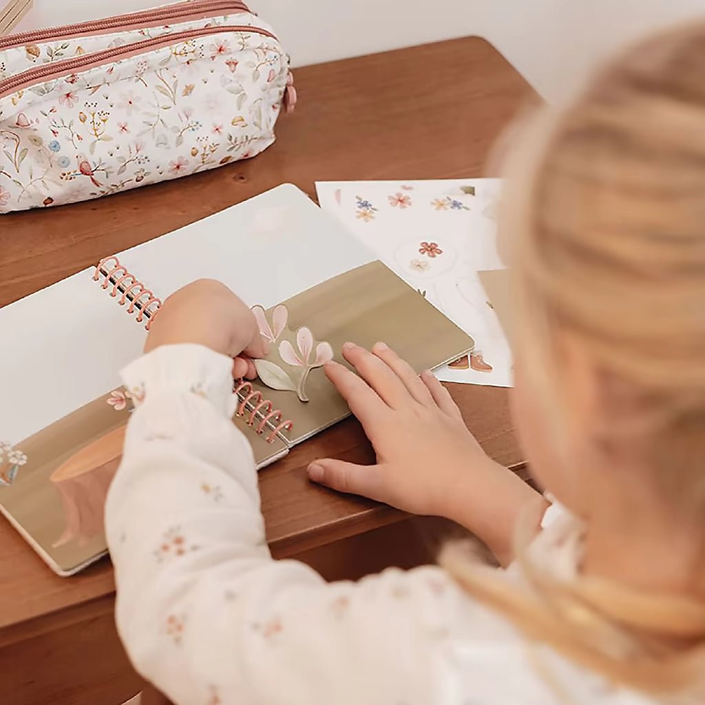 Kind plakt stickers in Little Dutch aankleedboek Fairy Garden, kleurrijke illustraties maken dit aankleedboek ideaal voor peuterboeken.