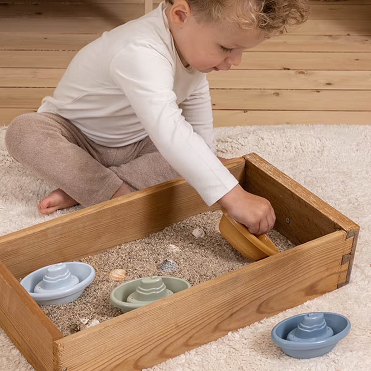 Kind speelt met Little Dutch Bad Bootjes in zandbak, veelzijdig badspeelgoed ook geschikt voor buiten.