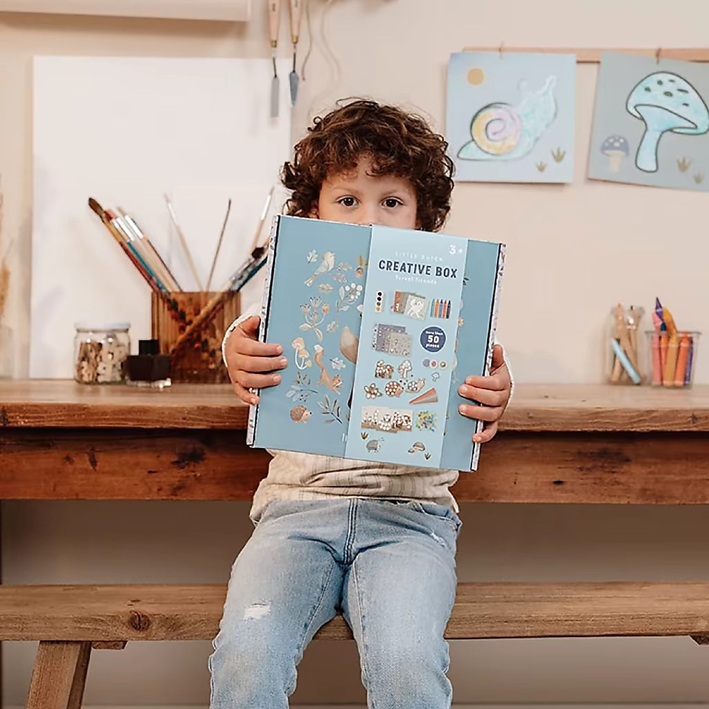 Peuter houdt Little Dutch Knutseldoos Forest Friends verpakking vast, ideaal voor knutselen met peuters thuis.