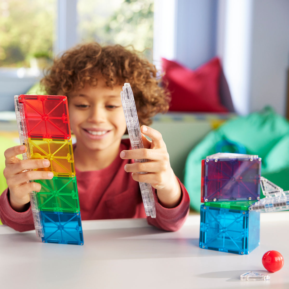 Kind toont magnetic magna tiles Rail Racers transparante knikkerbaan rail en gekleurde magnetische tegels