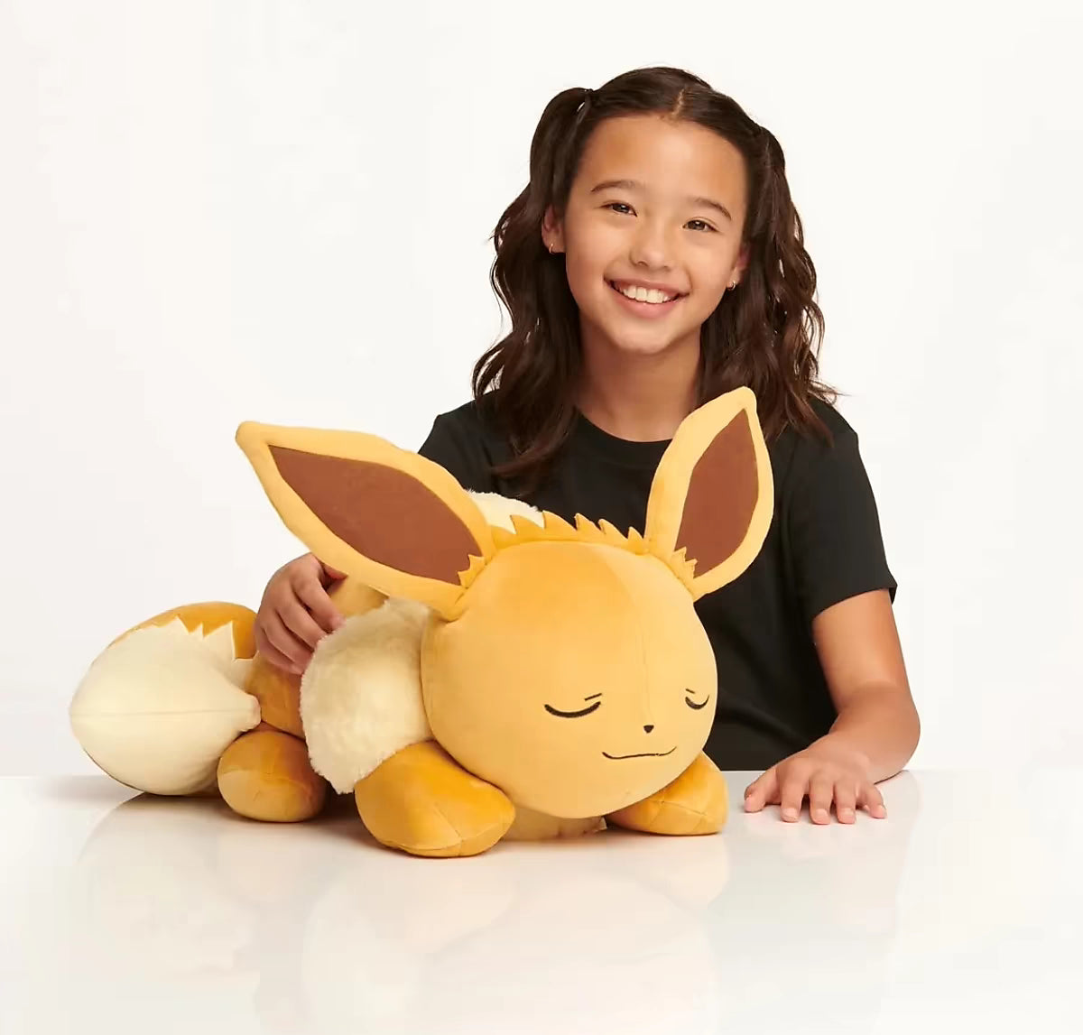 Sleeping Eevee knuffel Pokémon naast lachend kind, toont groot pluche ontwerp en geschikt als Pokémon cadeau voor jonge fans.