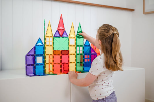 Meisje speelt met constructiespeelgoed, magnetische tegels om een kasteel te bouwen.