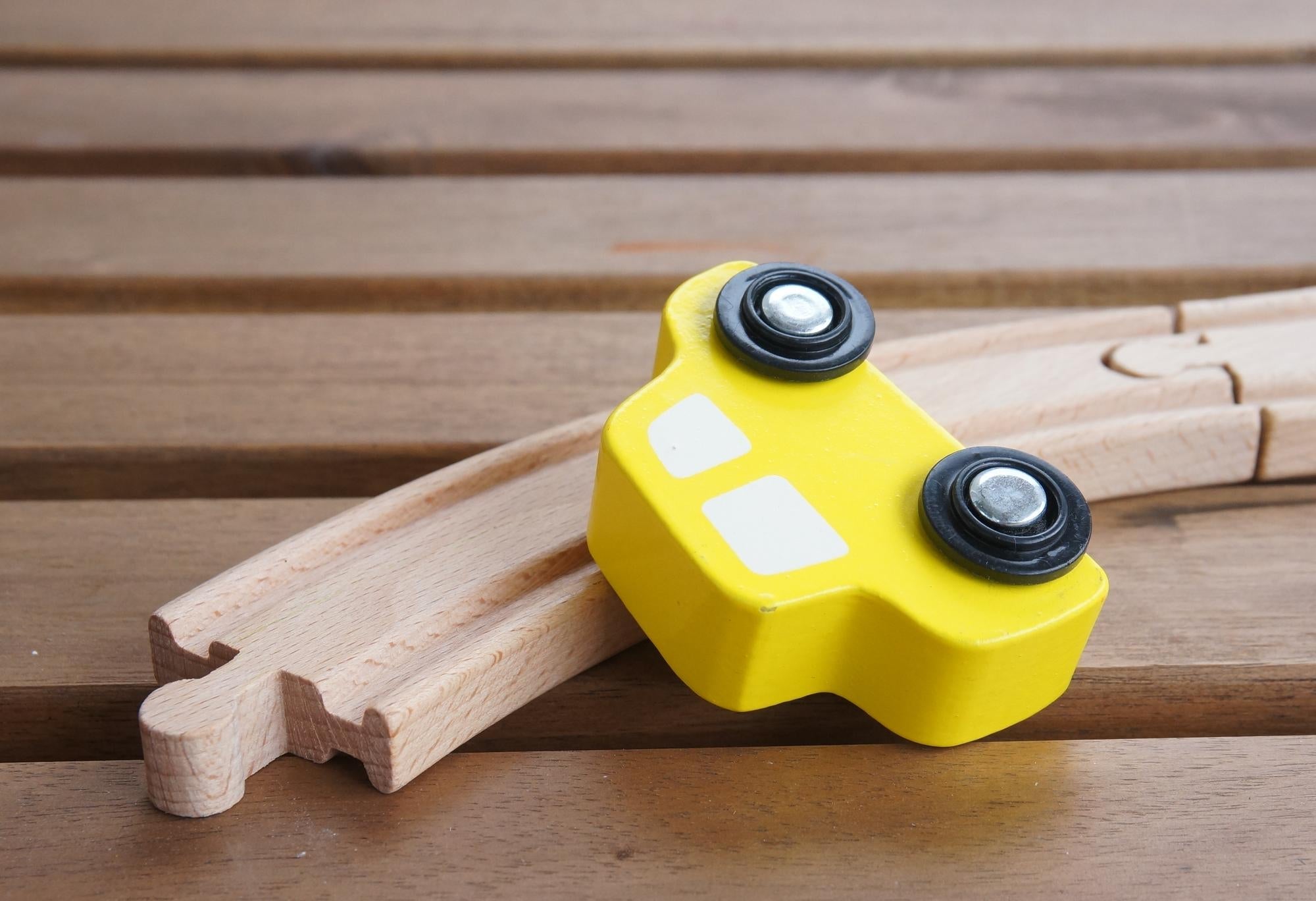 Houten educatief speelgoed, gele trein op houten rails, stimuleert motoriek en spelend leren bij jonge kinderen.