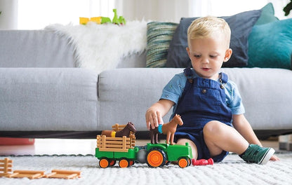 Jongentje bouwt met SmartMax My First Tractor SMX 222 magneet speelgoed, groene tractor met bruine paarden op vloerkleed