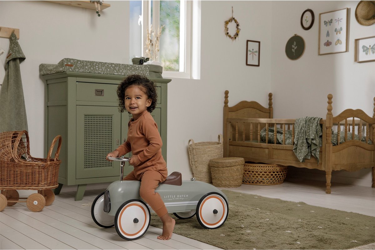 Kind rijdt op Little Dutch auto speelgoed in sfeervolle babykamer met natuurlijke kleuren