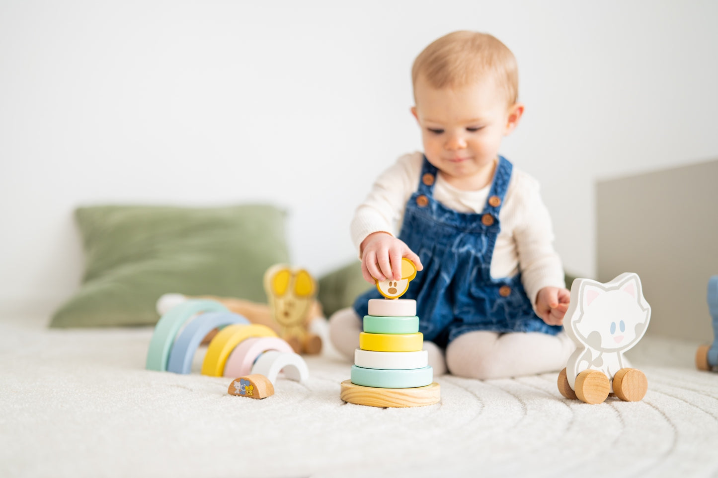 Baby zit met houten stapeltoren educatief speelgoed en Woezel en Pip figuurtje op speelkleed