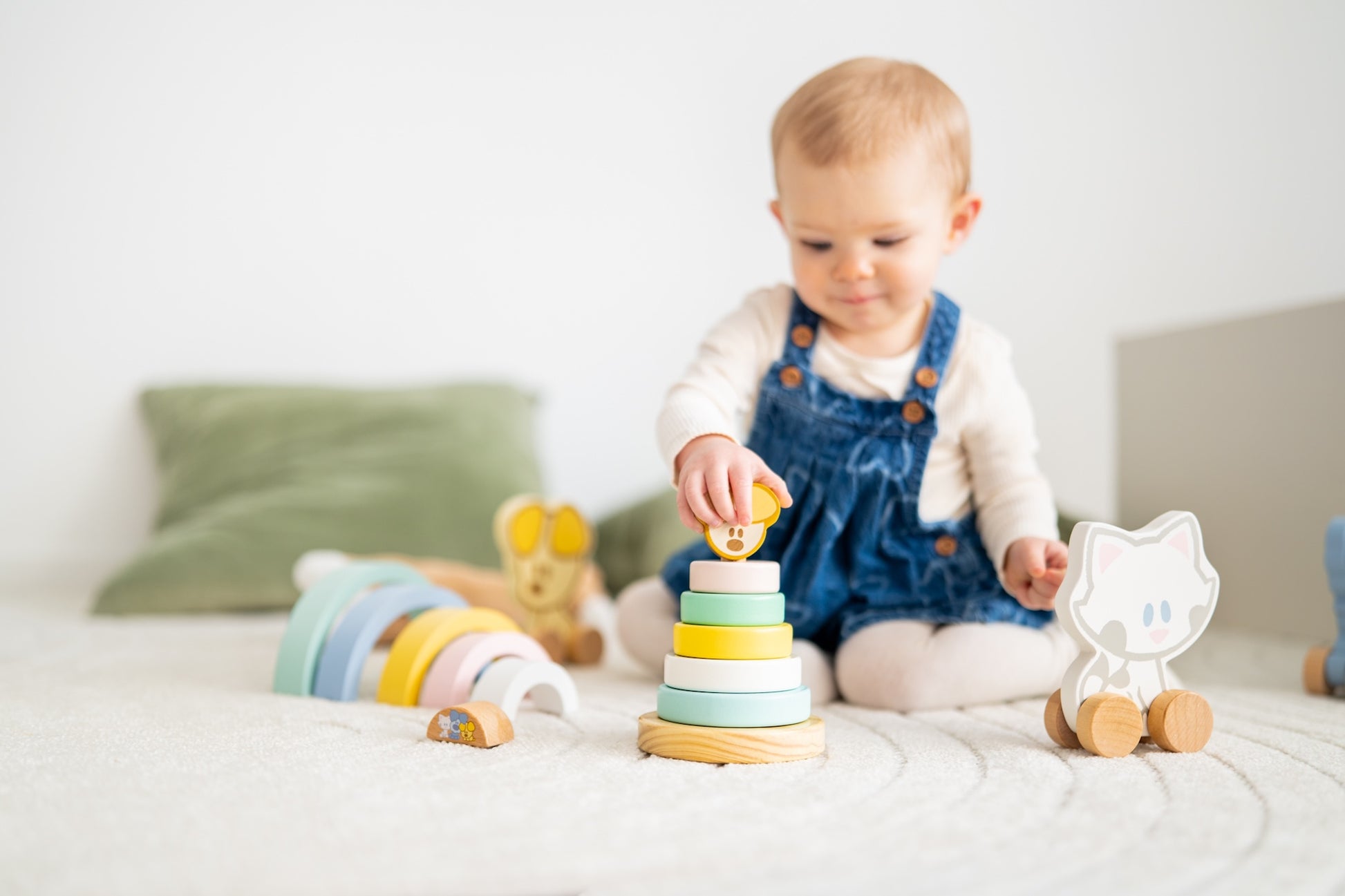 Baby zit met houten stapeltoren educatief speelgoed en Woezel en Pip figuurtje op speelkleed