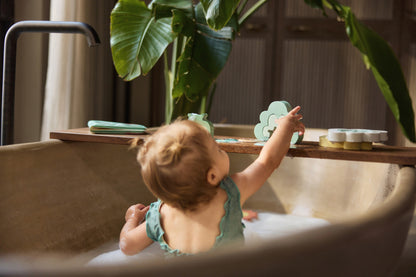 Baby speelt met Jollein badspeelgoed kangaroo en boom op houten plank boven badkuip met schuim