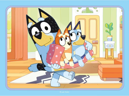 Bandit draagt Bluey en Bingo in de woonkamer, kleurrijke Ravensburger puzzelafbeelding voor peuters en kinderen.