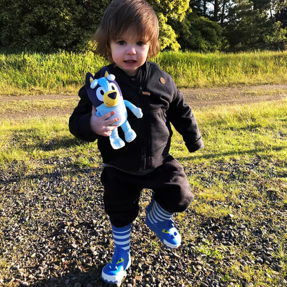 Peuter speelt buiten met Bluey pluche knuffel, een vrolijk speelvriendje en veilig sensorisch speelgoed.