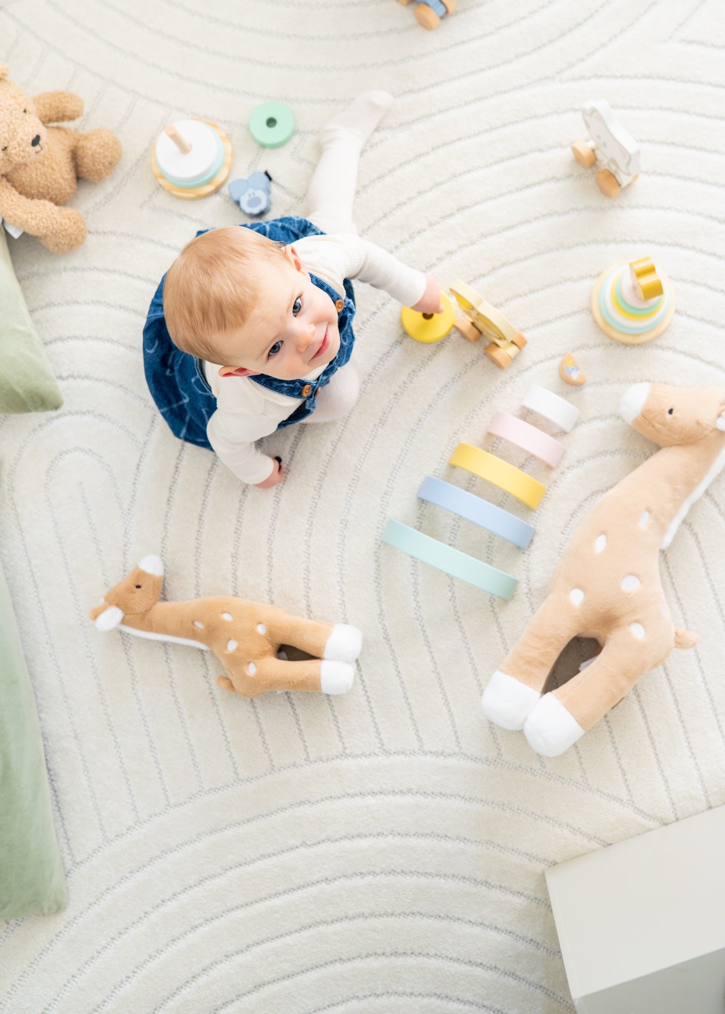 Bovenaanzicht baby spelend met sensorisch speelgoed, houten hertenknuffel en educatief speelgoed