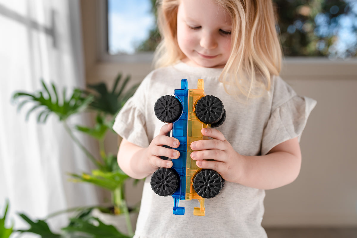 Meisje speelt met Cars Set 2 magnetische autos Connetix blauw geel gekoppeld, vooraanzicht kind