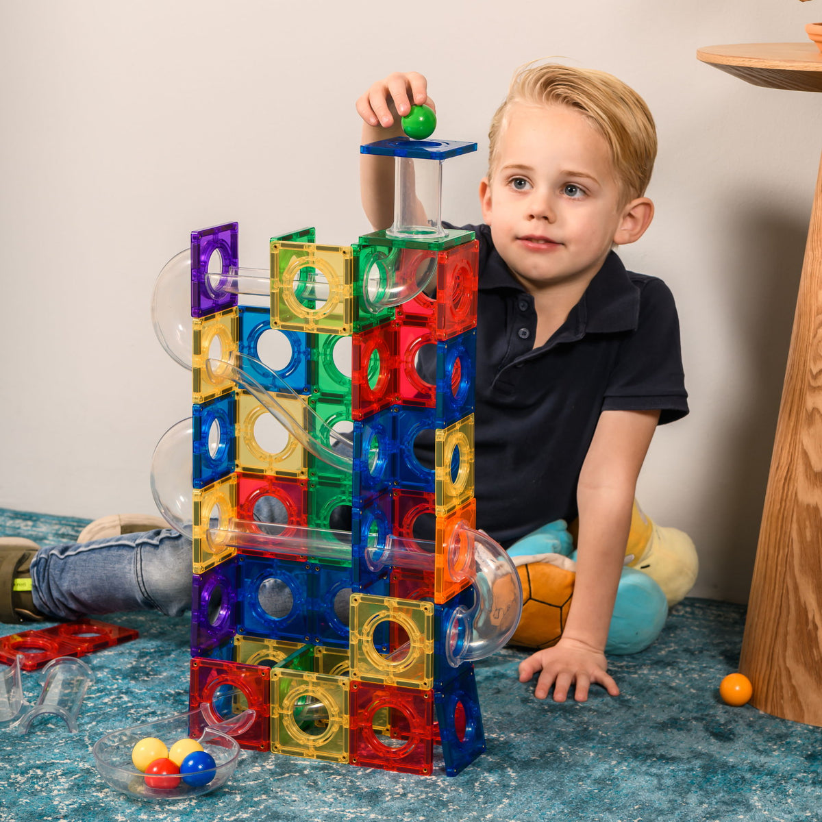 Kind bouwt coblo knikkerbaan toren met kleurrijke magnetische tegels en transparante knikkerglijbanen