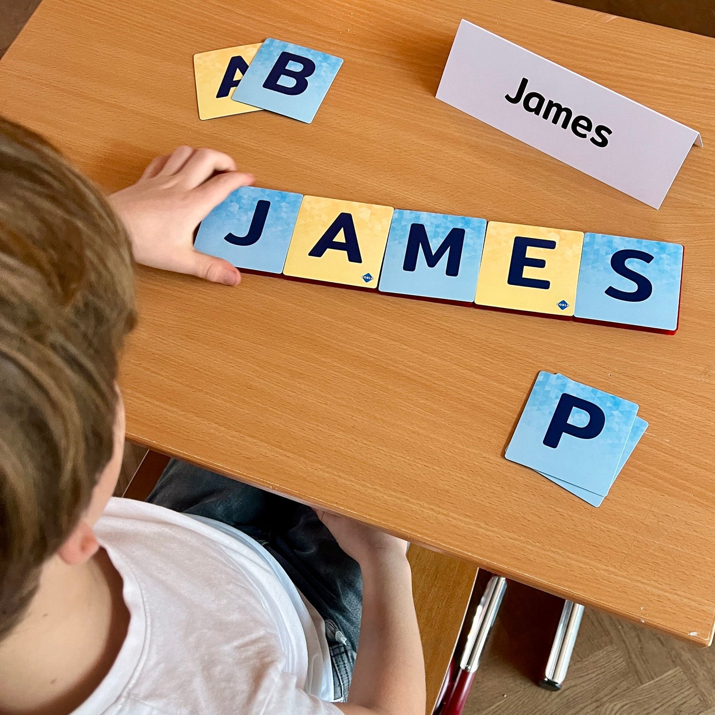 Kind legt naam James met Coblo magneten speelgoed magnetische letterkaarten op tafel