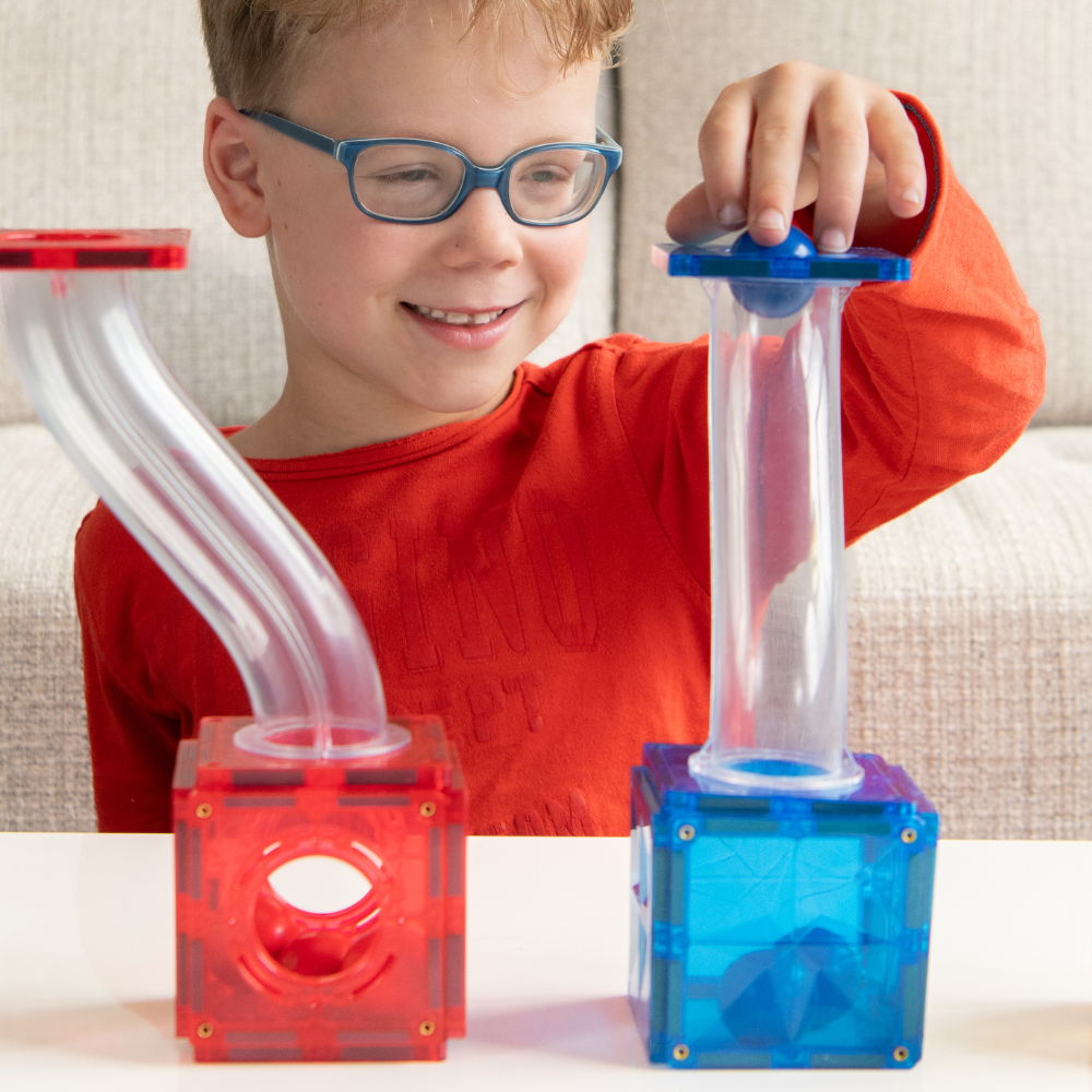 Jongen bouwt Coblo knikkerbaan met transparante magnetische bouwstenen rood en blauw detailfoto