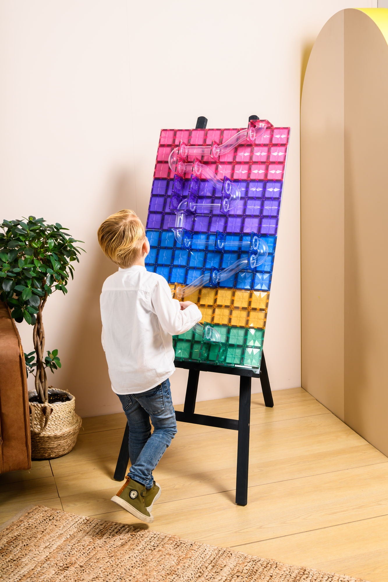 Kind speelt met Coblo magnetische bouwtegels knikkerbaan op staander in moderne kinderkamer interieur