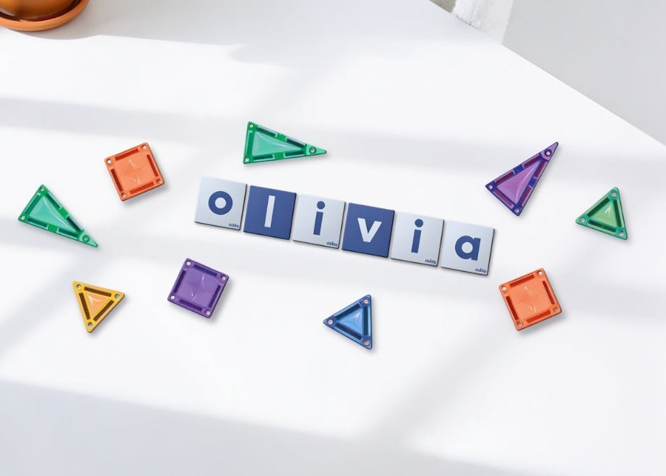 Coblo Mini toppers bovenaanzicht met naam Olivia gelegd op witte tafel met gekleurde magneet tegels