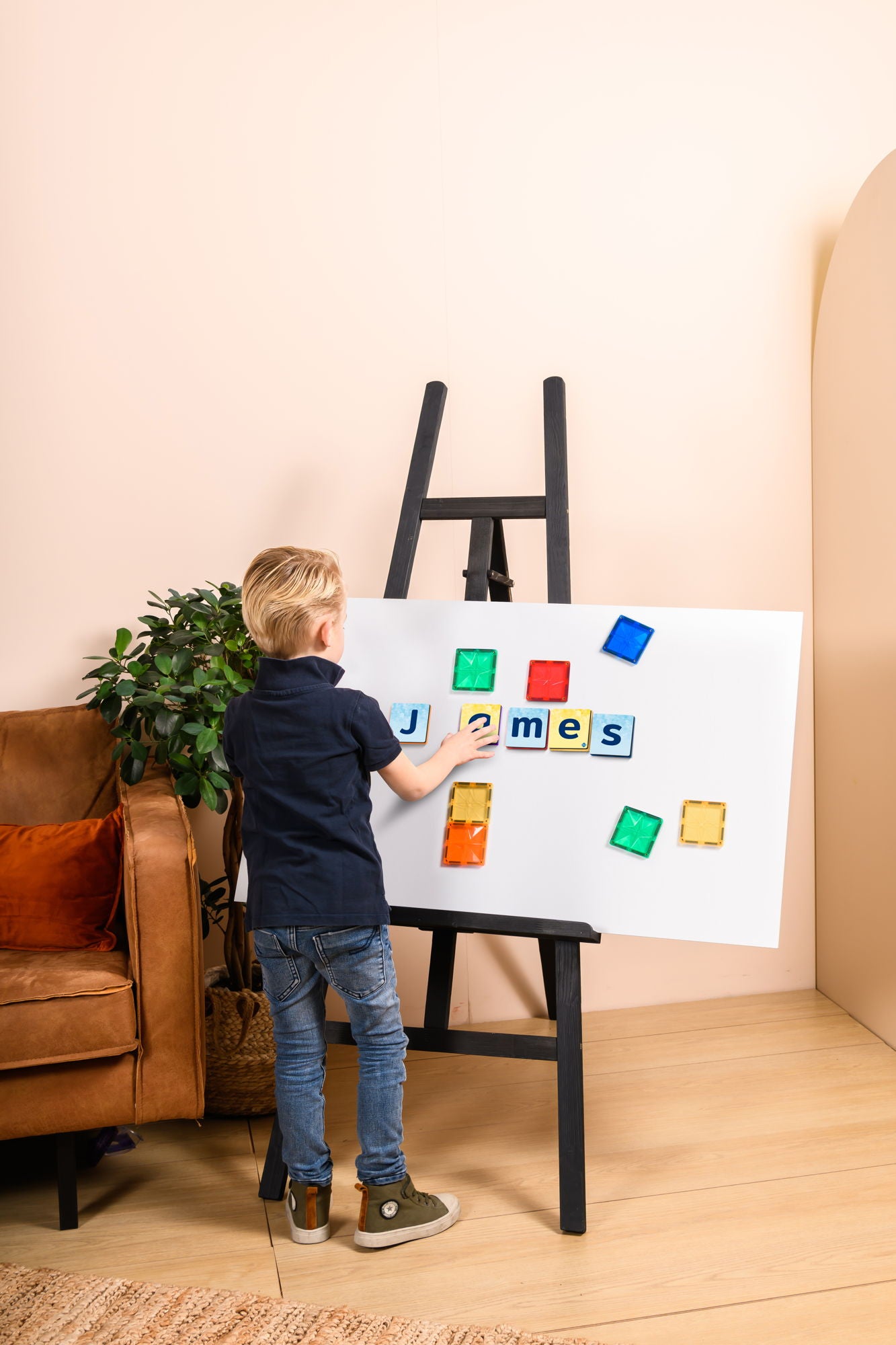 Kind speelt met Coblo speelgoed - jongen legt naam James op whiteboard met magnetische letters en blokken