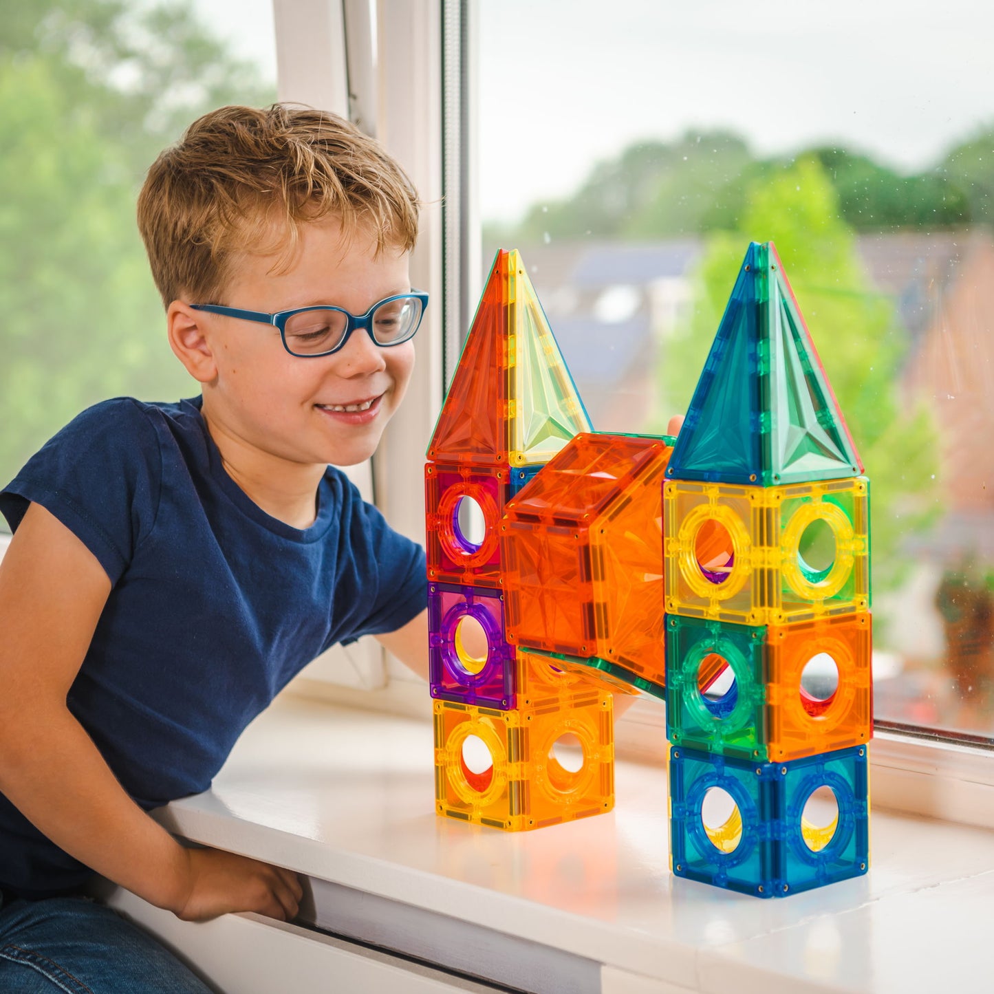 Kind speelt met Coblo zeshoek magnetisch speelgoed en bouwt kleurrijke torens bij het raam