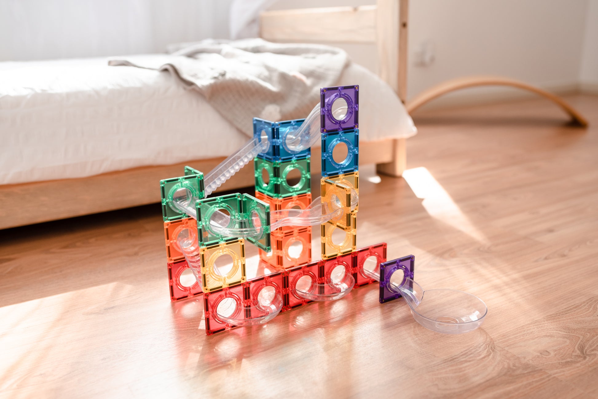 Connetix ball run detail foto met regenboogkleurige magneet tegels en transparante knikkerbuizen op vloer