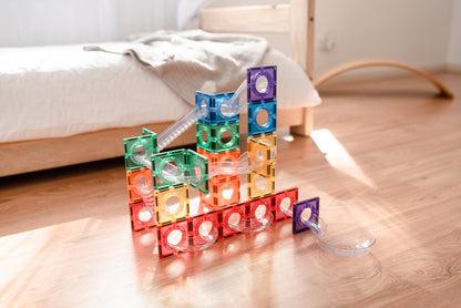 Connetix ball run detail foto met regenboogkleurige magneet tegels en transparante knikkerbuizen op vloer