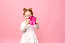 Vrolijk meisje houdt roze zeshoekige magneet tegel vast van Connetix Charity Pack Pink 20pc, roze achtergrond.