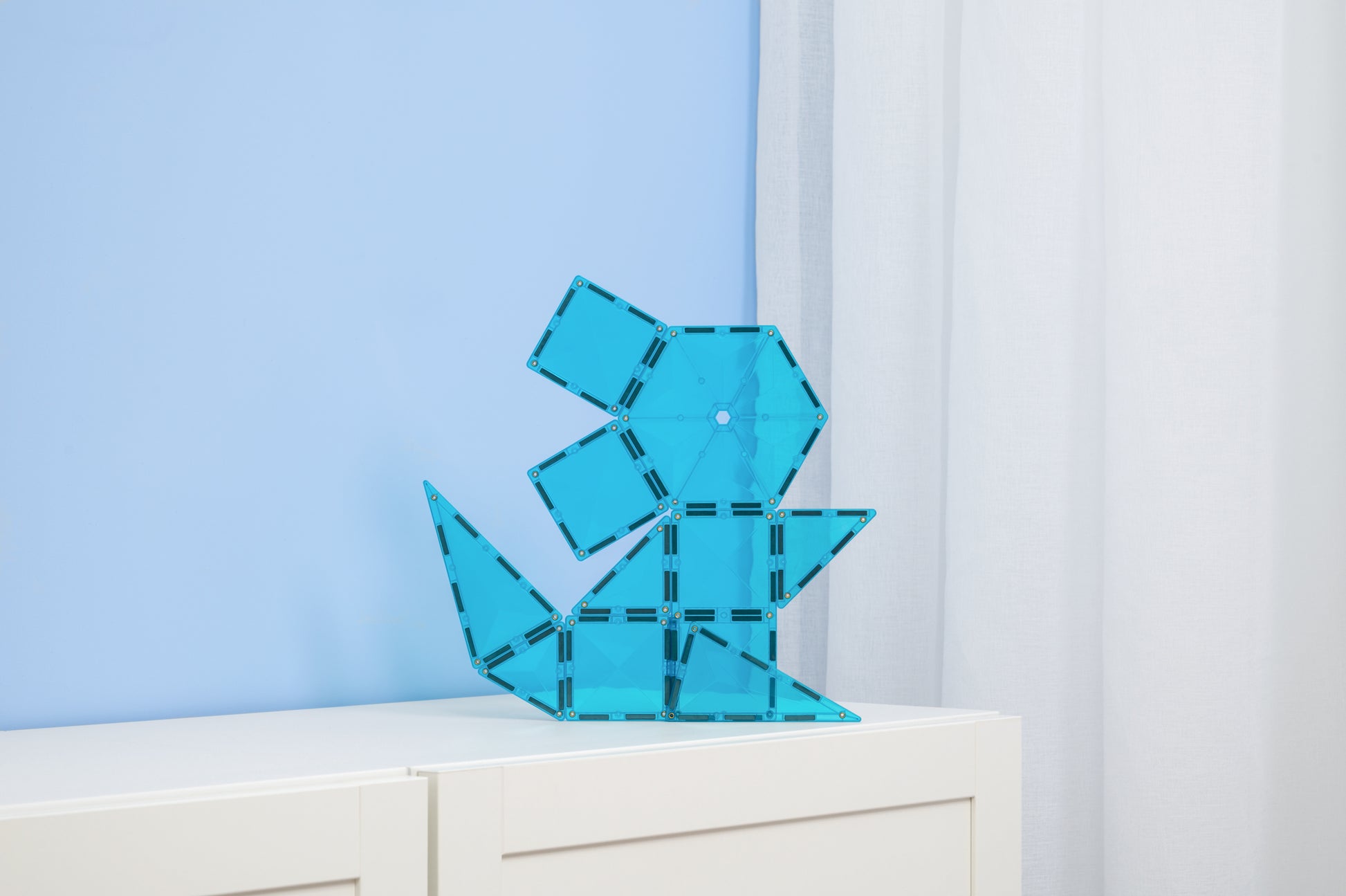 Connetix Charity Pack Teal 20pc – teal magnetische tegels gebouwd als dinosaurus op witte kast in kinderkamer.