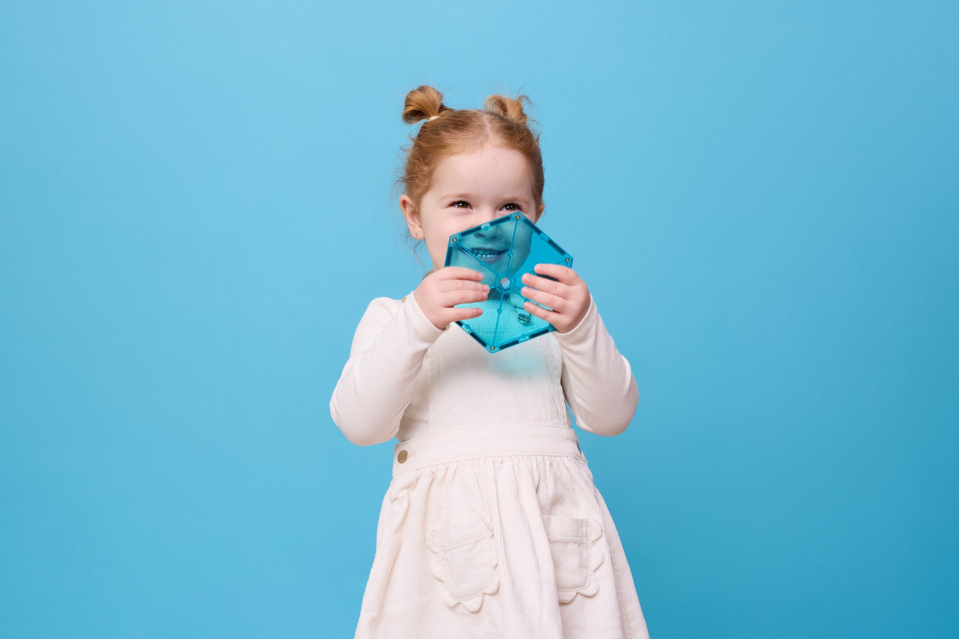 Connetix Charity Pack Teal 20pc – meisje houdt lachend een teal hexagon magnetische tegel vast op blauwe achtergrond.