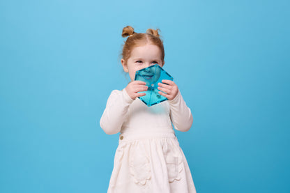 Connetix Charity Pack Teal 20pc – meisje houdt lachend een teal hexagon magnetische tegel vast op blauwe achtergrond.