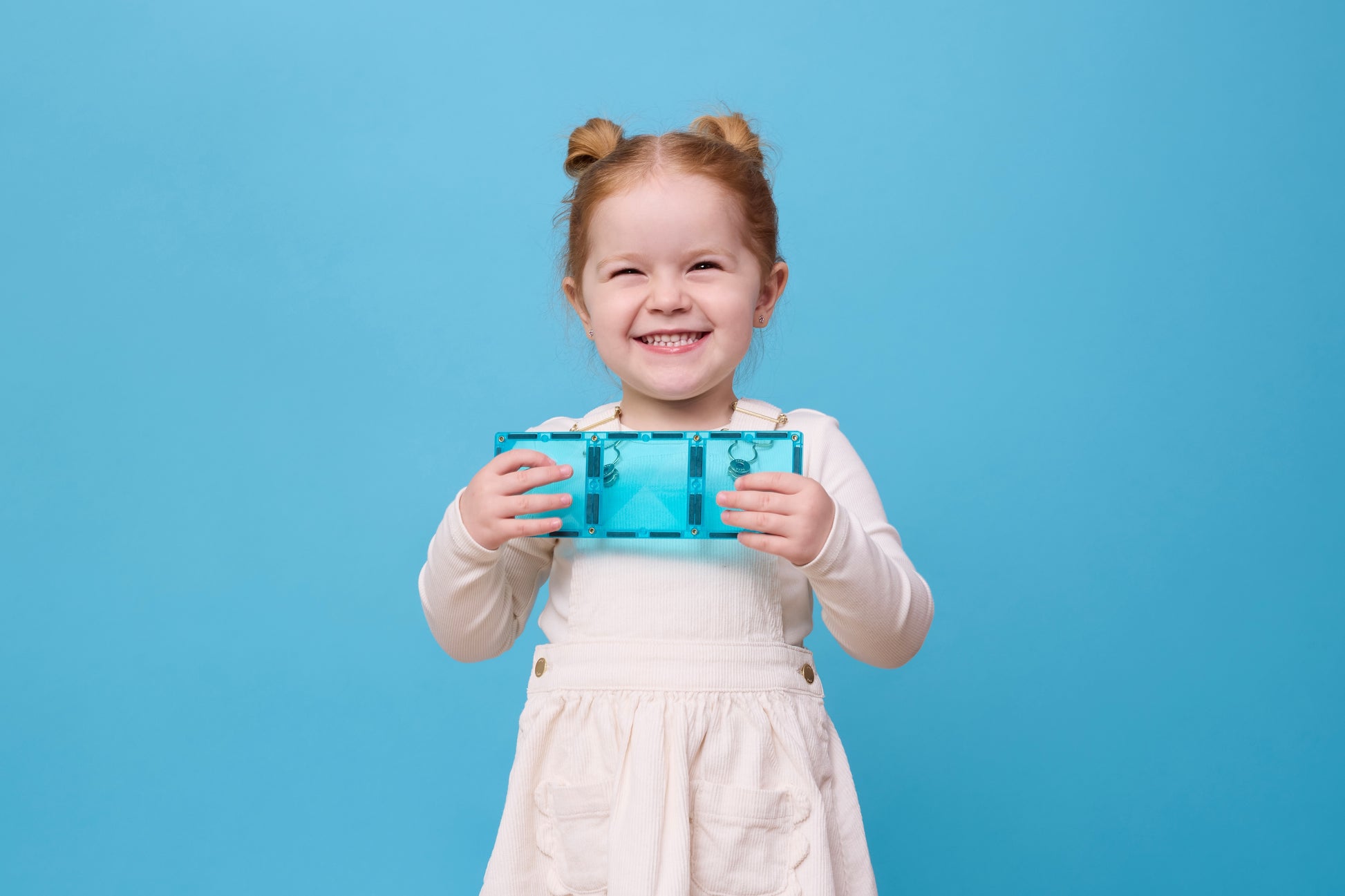 Connetix Charity Pack Teal 20pc – blij meisje toont lachend teal rechthoekige magnetische tegel op blauwe achtergrond.