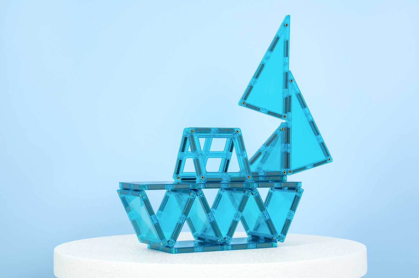 Connetix Charity Pack Teal 20pc – teal connetix tiles gebouwd als zeilboot op witte sokkel, lichtblauwe achtergrond.