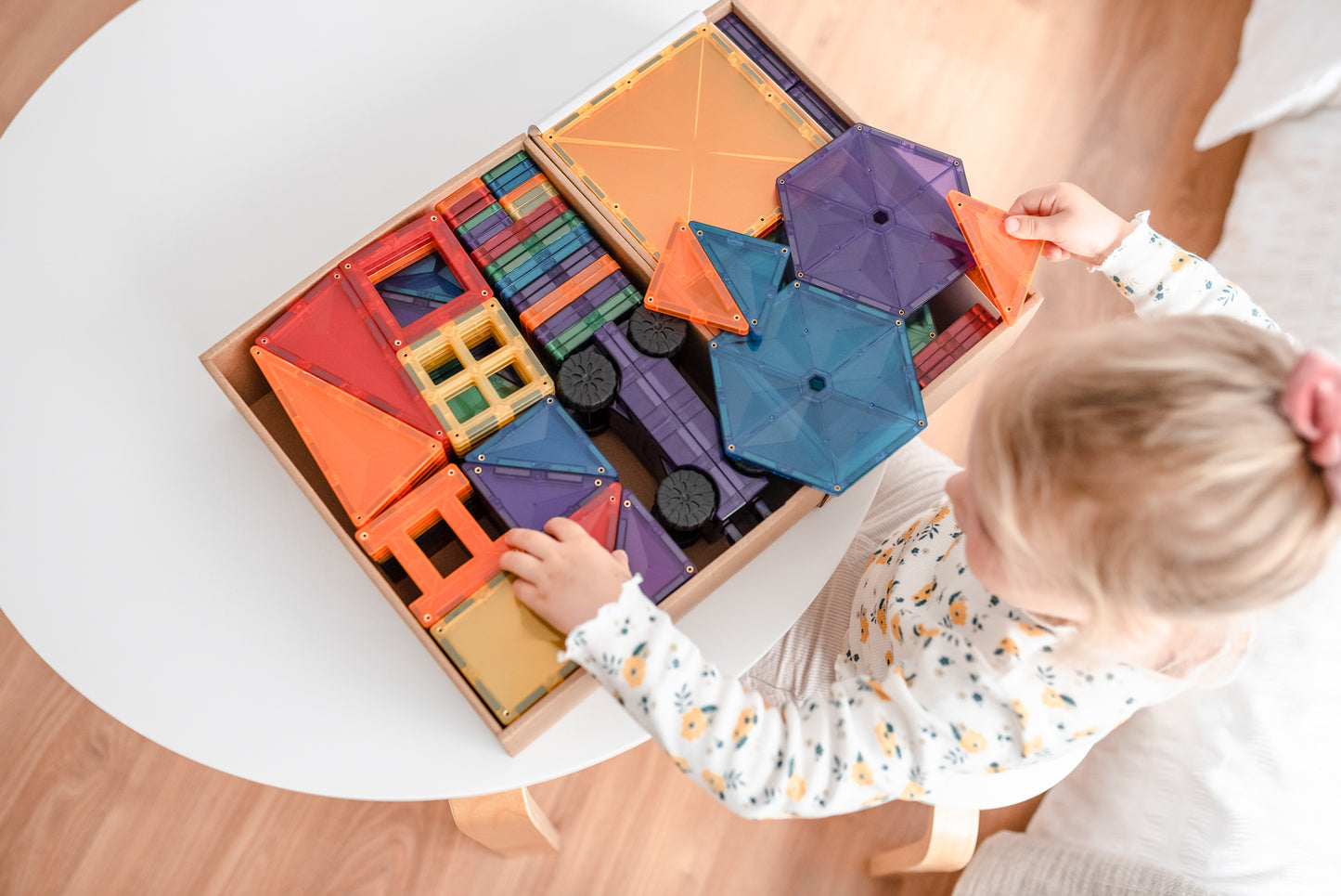 Connetix magneet speelgoed bovenaanzicht met kind dat kleurrijke magnetische bouwstenen sorteert in houten bak