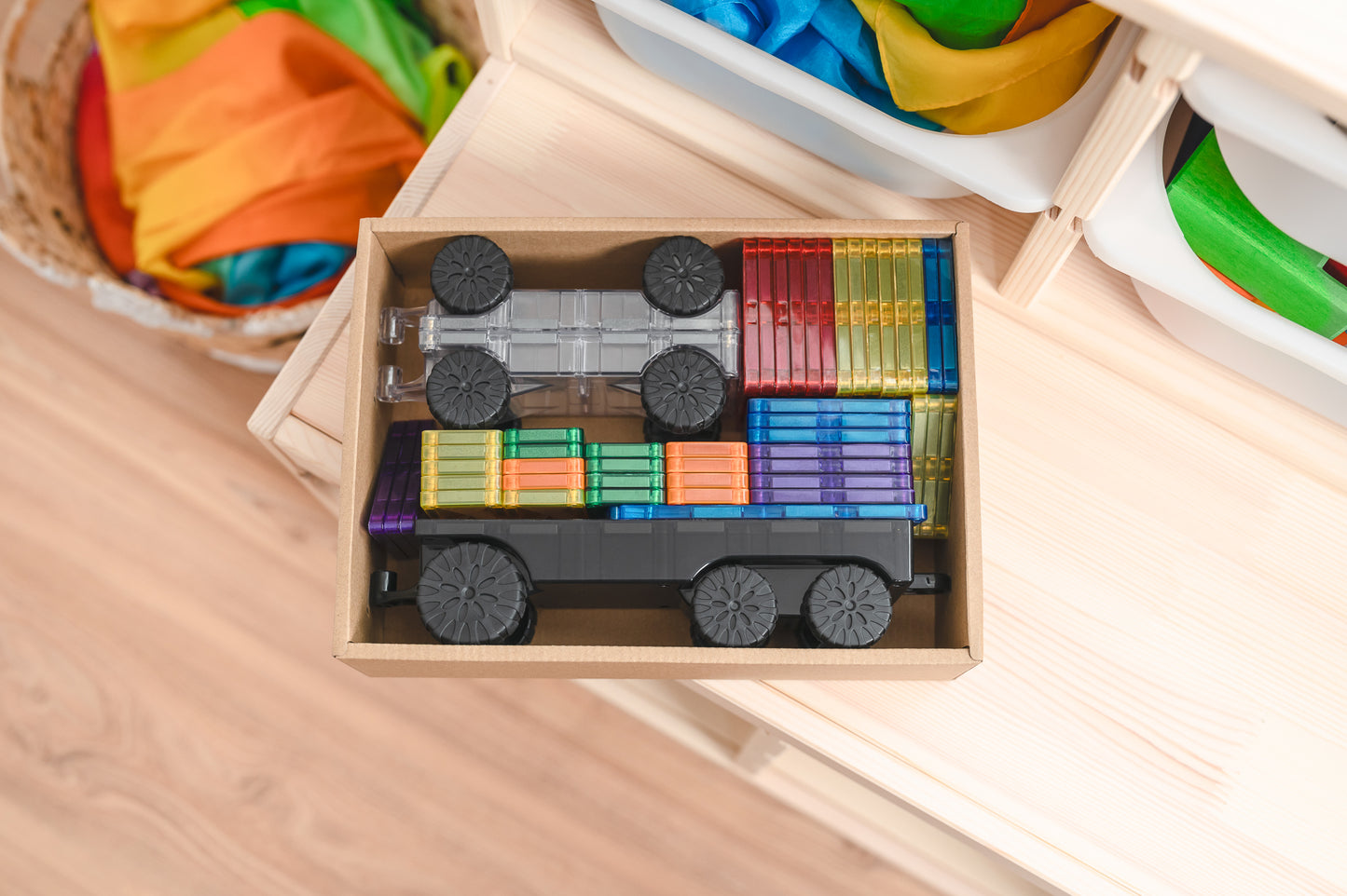 Bovenaanzicht Connetix magneet tegels Transport Pack in houten opbergbox met regenboogkleuren rijtuigen