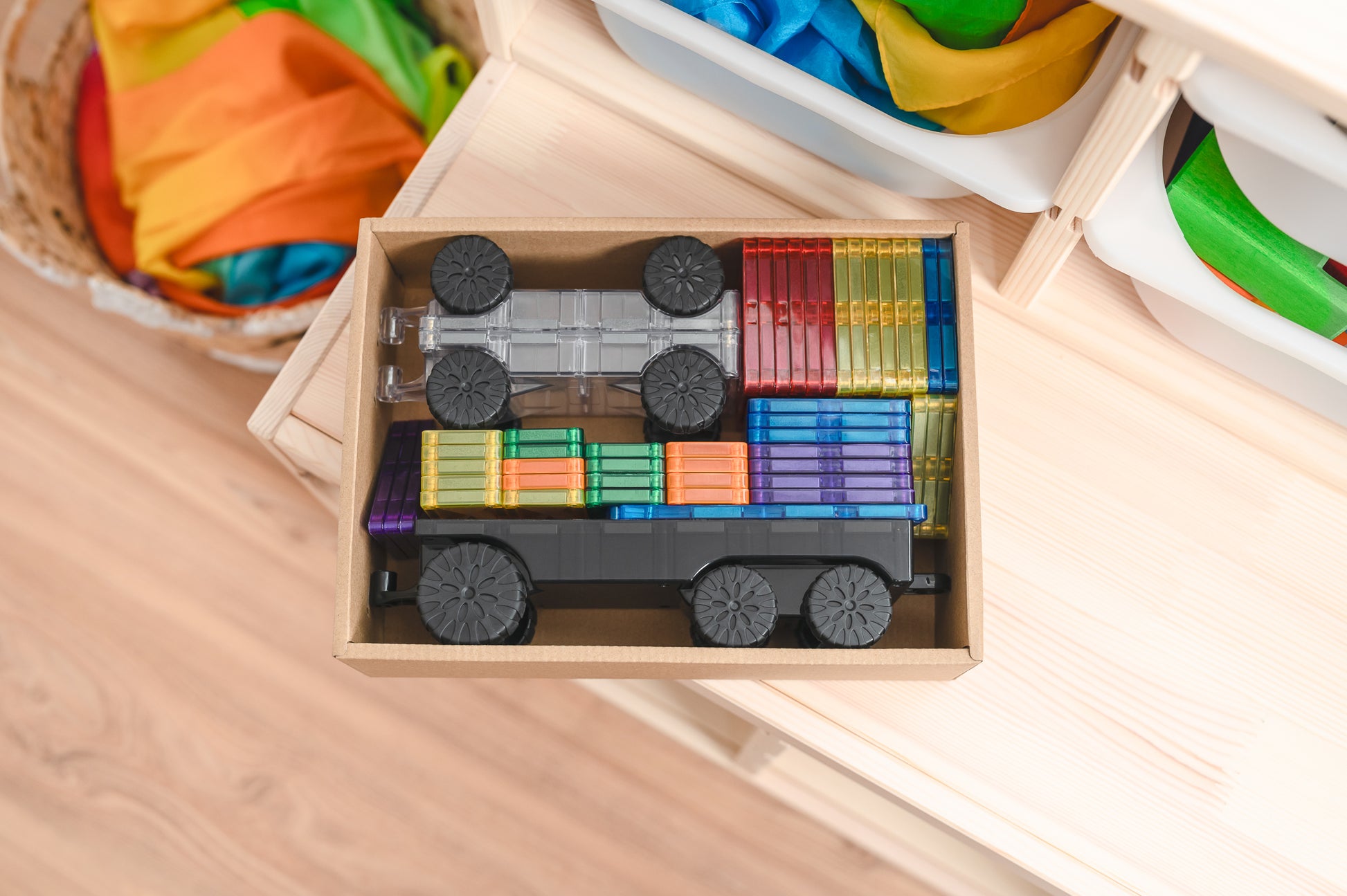 Bovenaanzicht Connetix magneet tegels Transport Pack in houten opbergbox met regenboogkleuren rijtuigen