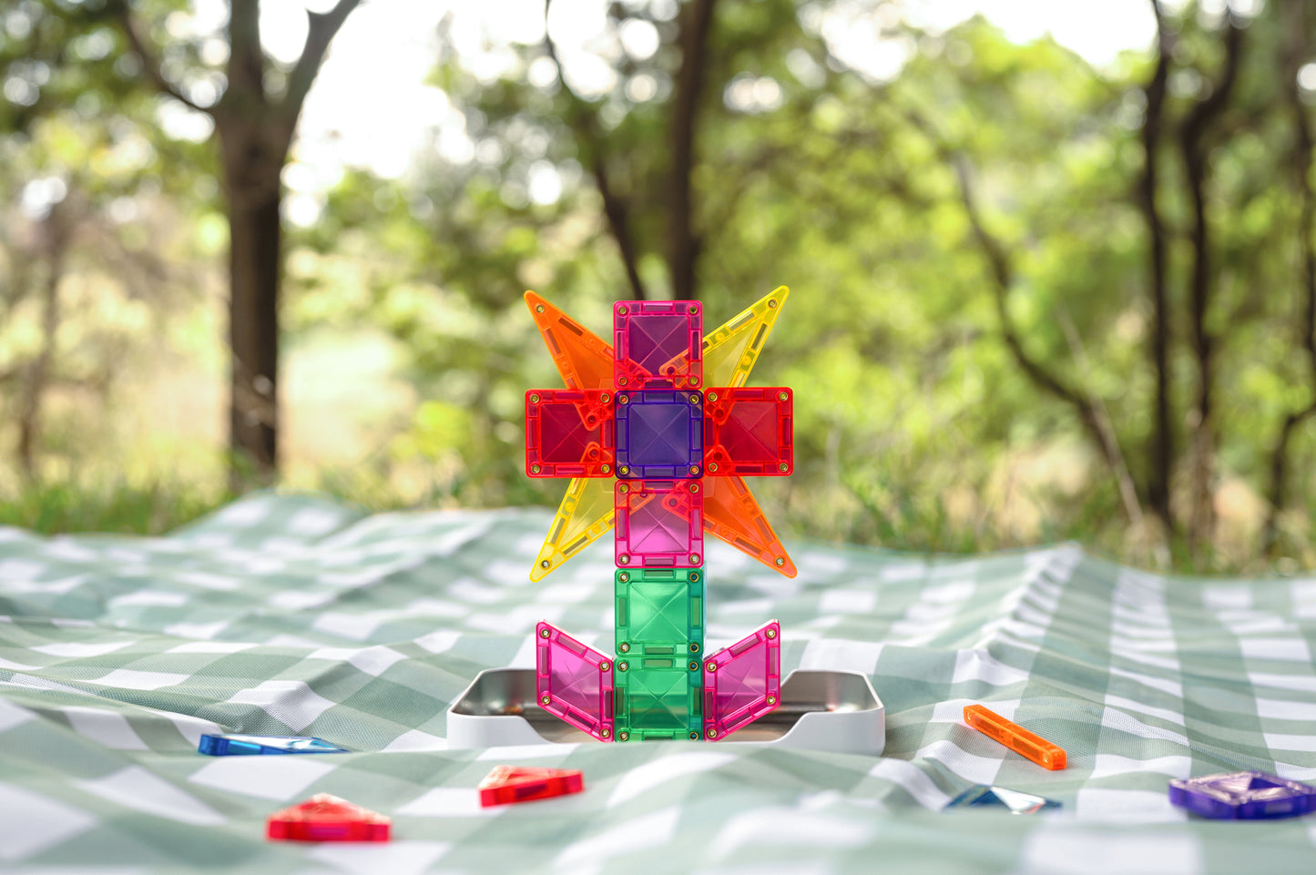 Connetix travel mini pack vliegtuig gebouwd met kleurrijke magneet tegels op picknickkleed buiten