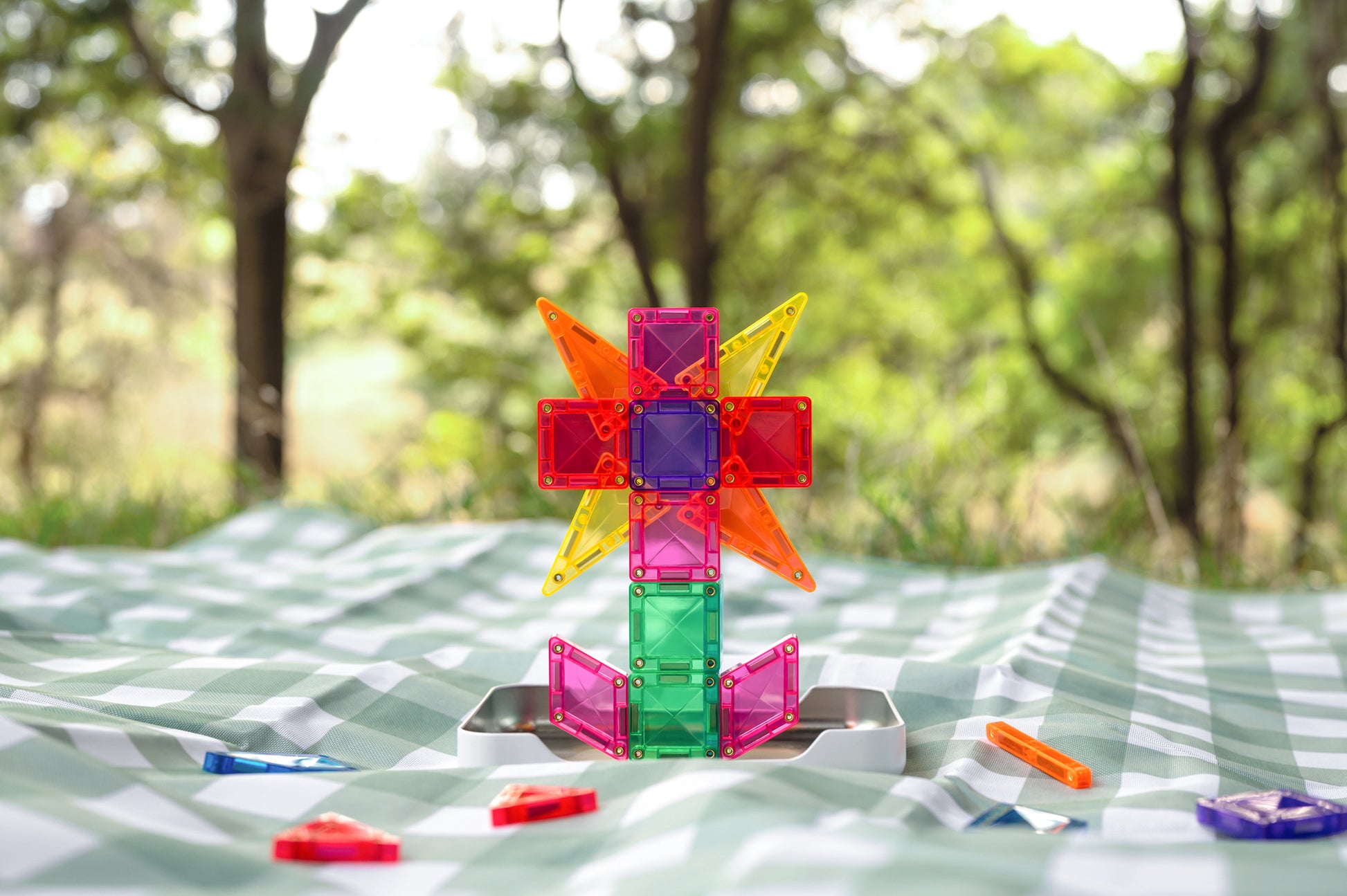 Connetix travel mini pack vliegtuig gebouwd met kleurrijke magneet tegels op picknickkleed buiten