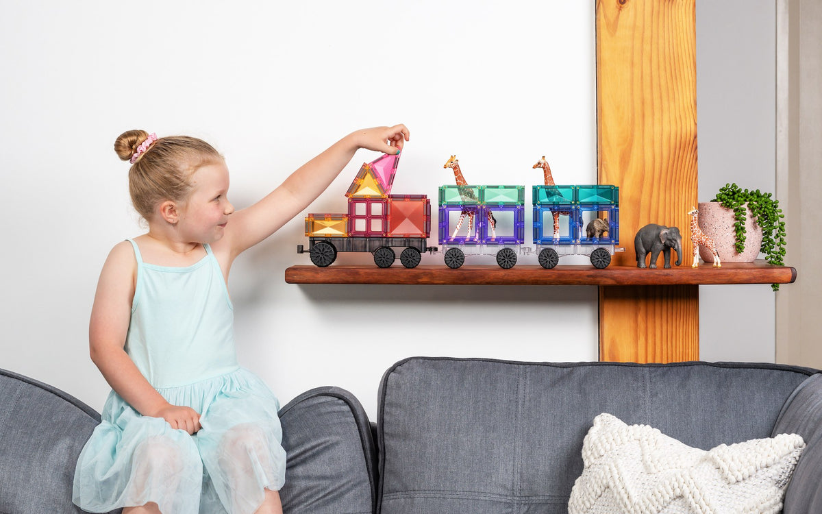 Connetix magnetisch speelgoed pastel trein met giraffes meisje spelend op houten plank witte achtergrond