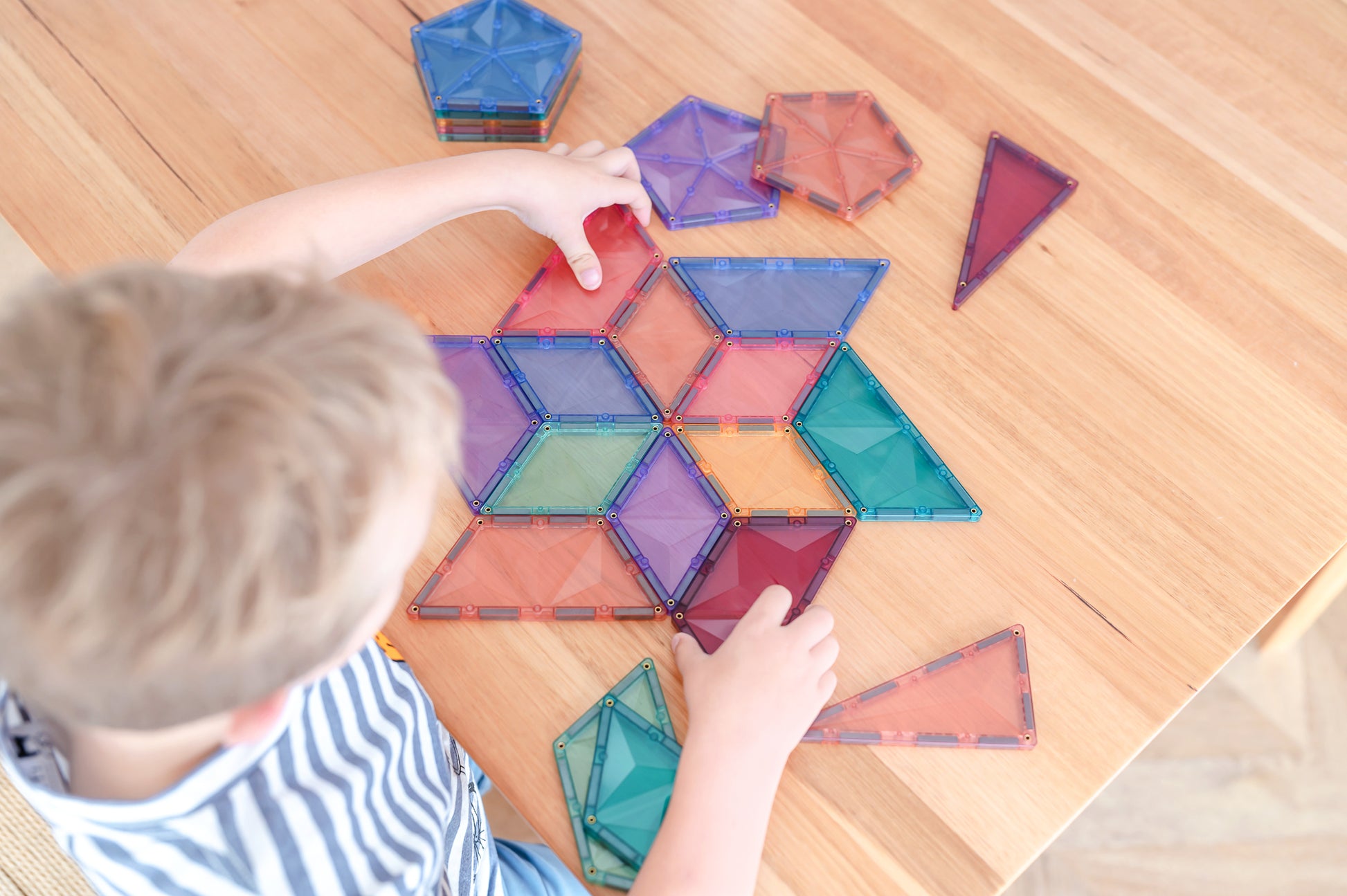 Bovenaanzicht kind legt patronen met Connetix Pastel Shape Expansion Pack 48pc magnetische bouwstenen