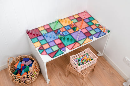 Bovenaanzicht speeltafel bedekt met Connetix Pastel Starter Pack 64pc magneet tegels en houten poppetjes
