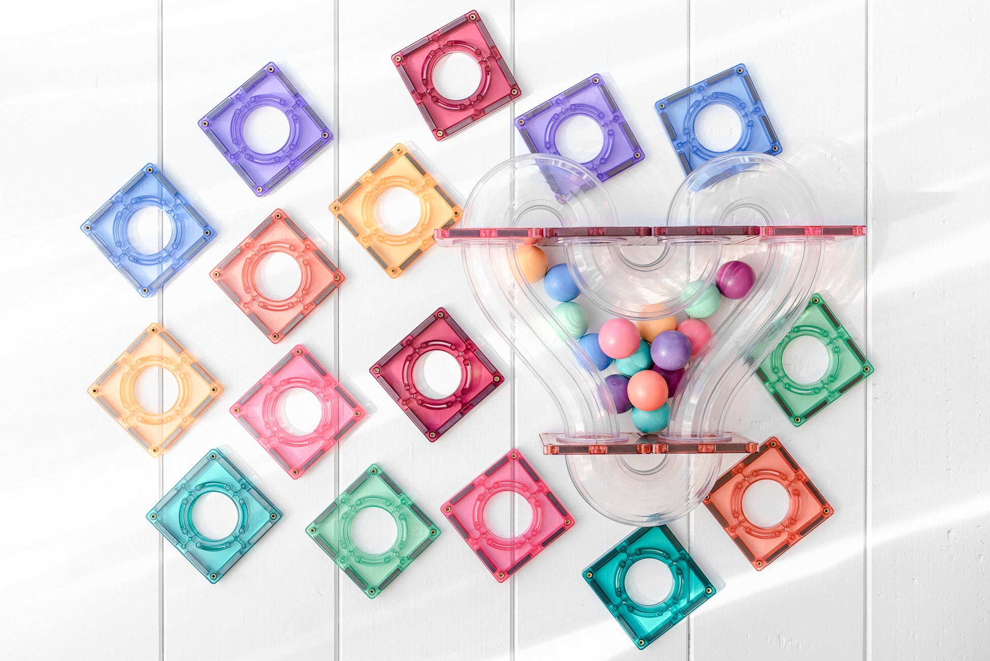Flatlay van Connetix Pastel Ball Run Pack 106 pc met kleurrijke magneet tegels, glijbaan en pastel knikkers