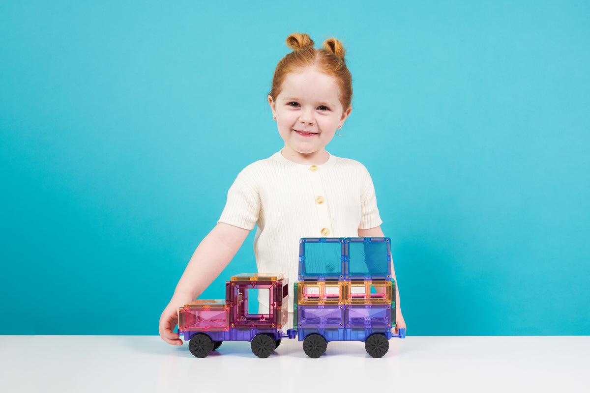 Meisje speelt met Connetix Pastel Motion Pack 26 magneten speelgoed trein in paarse en roze tinten